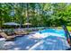 Backyard boasts an in-ground pool with lounge seating, shaded umbrellas, and manicured landscaping at 7003 Tara Dr, Villa Rica, GA 30180