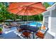 Relaxing poolside area with a dining table, lounge chairs, umbrellas, and lush greenery in the background at 7003 Tara Dr, Villa Rica, GA 30180