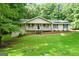 Inviting single-Gathering home with a charming front porch, complemented by a lush green lawn and mature trees at 185 Downybrook Ln, Fayetteville, GA 30215