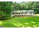 Inviting single-Gathering home with a charming front porch, complemented by a lush green lawn and mature trees at 185 Downybrook Ln, Fayetteville, GA 30215