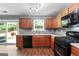 Well-lit kitchen includes wood floors, matching cabinets, black appliances, and backyard view at 1209 Polk Xing, Mcdonough, GA 30252