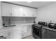 Well-organized laundry room with white cabinets, gray subway tile backsplash, and modern appliances at 2775 Club Valley Ct, Jonesboro, GA 30236