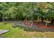 Beautiful backyard featuring lush trees, colorful potted plants, and a charming brick retaining wall at 3511 Cherry Blossom Ct, Loganville, GA 30052