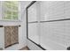 White subway tile surrounds a tub and shower with a black framed glass enclosure, along with a towel bar at 3511 Cherry Blossom Ct, Loganville, GA 30052