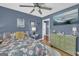 Bedroom with a ceiling fan, blue walls, hardwood floors, window view of the outside, and a television at 3511 Cherry Blossom Ct, Loganville, GA 30052