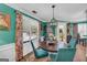 This dining area features a dark wood table, teal chairs, a modern chandelier and view into the side and front yards at 3511 Cherry Blossom Ct, Loganville, GA 30052