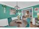 Dining area with hardwood floors, modern chandelier, teal accent wall, and furniture adjacent to living space at 3511 Cherry Blossom Ct, Loganville, GA 30052