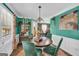 Dining area with view to kitchen with hard wood floors, teal accent wall, modern chandelier, and white trim at 3511 Cherry Blossom Ct, Loganville, GA 30052