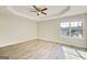 A bright bedroom features a ceiling fan, tray ceiling, and a window letting in natural light and illuminating the hardwood floors at 1399 Cutters Mill Dr, Lithonia, GA 30058