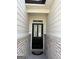 The front door is black with two glass panels, framed by brick and white siding at 13709 Whitman Ln, Covington, GA 30014