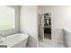 Bright bathroom featuring a modern soaking tub, marble tile, and an open doorway to the Primary bedroom at 209 Osier Dr, Mcdonough, GA 30252