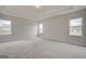 Spacious bedroom with three windows, tray ceiling, and soft carpeting, offering a serene and light-filled retreat at 402 Westmarch Cir # 285A, Loganville, GA 30052