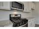 Close-up of stainless steel appliances, granite countertops, white cabinets and tile backsplash at 402 Westmarch Cir # 285A, Loganville, GA 30052