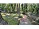 Exterior view of a brick path in the backyard leading through mature trees and landscaping at 4710 Cedar Brook Se Dr, Conyers, GA 30094