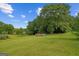 Grassy backyard featuring mature trees and a fenced enclosure in the background at 9360 Ward Rd, Winston, GA 30187