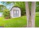 Charming shed with double doors, situated on a green lawn amidst mature trees, adds character to the property at 741 Greenhill Ne Dr, Conyers, GA 30012