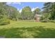 Expansive backyard with green lawn, white fence, and view of additional structure, creating a spacious outdoor area at 115 Shoal Creek Dr, Sharpsburg, GA 30277