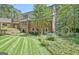 Expansive backyard features manicured lawn, garden, brick patio, and charming details for outdoor enjoyment at 115 Shoal Creek Dr, Sharpsburg, GA 30277