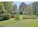 Picturesque backyard featuring a white picket fence, lush lawn, and mature trees, with a glimpse of the house at 115 Shoal Creek Dr, Sharpsburg, GA 30277