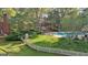 A backyard showcasing a pool, patio area, well-maintained lawn, and lush greenery with a white picket fence at 115 Shoal Creek Dr, Sharpsburg, GA 30277