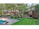 A backyard view featuring a large brick home, a swimming pool, and a well-manicured lawn and landscaping at 115 Shoal Creek Dr, Sharpsburg, GA 30277