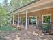 Covered brick patio featuring rocking chairs, sliding doors, and views of the serene backyard and garden at 115 Shoal Creek Dr, Sharpsburg, GA 30277