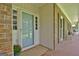 Charming blue front door with sidelights and a covered porch with a brick floor at 115 Shoal Creek Dr, Sharpsburg, GA 30277
