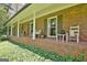 Charming brick front porch features classic columns, rocking chairs, and views of the landscaped yard at 115 Shoal Creek Dr, Sharpsburg, GA 30277