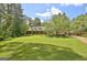 Stunning brick home with a lush, green lawn, mature trees, and rocking chair front porch at 115 Shoal Creek Dr, Sharpsburg, GA 30277