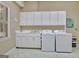 Bright laundry room with white cabinets, sink, and side-by-side washer and dryer at 115 Shoal Creek Dr, Sharpsburg, GA 30277