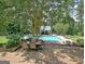 Backyard with a large pool, brick patio, landscaping, and a pool house, ideal for outdoor enjoyment and relaxation at 115 Shoal Creek Dr, Sharpsburg, GA 30277