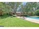 Backyard with a sparkling pool, lounge chairs, and lush greenery, ideal for outdoor relaxation and entertainment at 115 Shoal Creek Dr, Sharpsburg, GA 30277