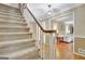 Carpeted staircase with wood railing, leading to a living room with hardwood floors and natural light at 115 Shoal Creek Dr, Sharpsburg, GA 30277