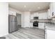 Spacious kitchen with stainless steel appliances, white cabinets, and gray wood-look flooring at 448 Prescott Way, Villa Rica, GA 30180