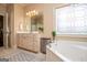 Well-lit bathroom featuring a large vanity and a corner bathtub with a decorative window at 713 Birkdale Blvd, Carrollton, GA 30116