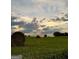 Scenic field with hay bales and barbed wire fence under a cloudy sky at 360 Morgan Mill Rd, Brooks, GA 30205