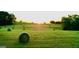 Scenic view of a field with round hay bales, illuminated by the warm glow of the setting sun at 360 Morgan Mill Rd, Brooks, GA 30205