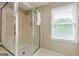 Clean bathroom featuring glass-enclosed shower, neutral tile, and bright natural light from the window at 3502 Village Green Dr, Roswell, GA 30075