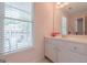 Bright bathroom with a white vanity, neutral tile floors, and a large window providing natural light at 3502 Village Green Dr, Roswell, GA 30075