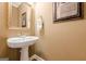 Stylish half-bathroom with a pedestal sink, decorative mirror, and warm, neutral wall color at 3502 Village Green Dr, Roswell, GA 30075