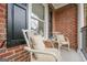 Front porch seating featuring a chair, wrought-iron railing, brick exterior, and black shutters at 3502 Village Green Dr, Roswell, GA 30075