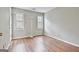 Bright bedroom with laminate wood floors, two windows, and a simple standing lamp at 128 Rubicon Rd, Peachtree City, GA 30269