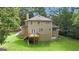 Exterior back view of a home featuring a deck and lush lawn surrounded by mature trees at 115 Rockhurst Chase, Tyrone, GA 30290