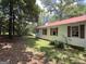 Exterior view showcases the home's siding, red roof and trim, and the naturally landscaped yard at 2306 Old Lower River Rd, Douglasville, GA 30135