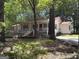 Charming single-story home with a red roof, inviting porch, and well-maintained yard nestled among mature trees at 2306 Old Lower River Rd, Douglasville, GA 30135
