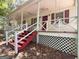 Inviting front porch with swing and fan, framed by white railings and red steps, nestled among lush greenery at 2306 Old Lower River Rd, Douglasville, GA 30135