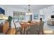 Staged dining room features a long wood table, modern chandelier, and large window at 110 Chardonnay Oaks Dr, Mcdonough, GA 30252