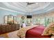 Serene main bedroom featuring tray ceilings, dresser, sitting area, and scenic backyard views, offering comfort and style at 606 Wingspread, Peachtree City, GA 30269