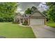Charming brick home with an attached two car garage, manicured lawn, and mature trees at 9187 Golfside Cir, Covington, GA 30014