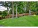View of backyard featuring a manicured lawn, tall trees, and a wooden fence at 705 Lawton Bridge Sw Rd, Smyrna, GA 30082
